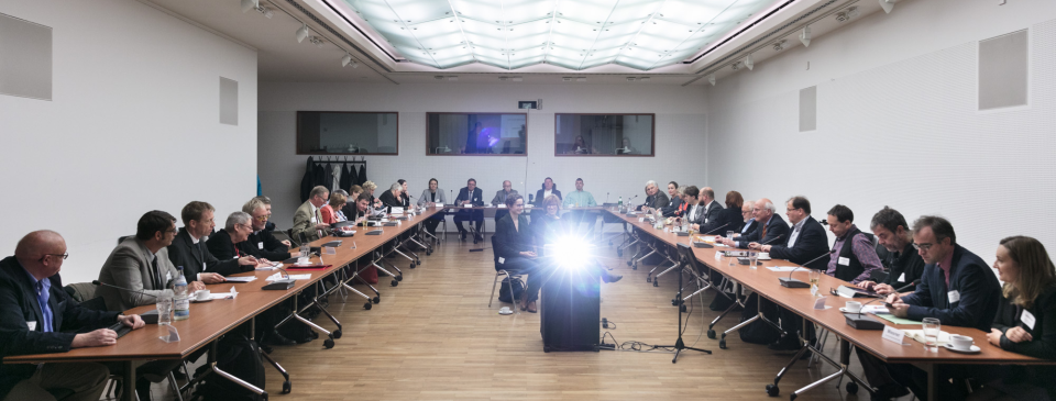 Konferenzsaal im Kleisthaus: Mitglieder des Expertenkreises und der Bundesfachstelle sitzen an einem U-förmigen Tisch und diskutieren. In der Mitte strahlt ein Projektor, dahinter sitzen zwei Gebärdensprachdolmetscherinnen. Foto: Gregor Schmidt