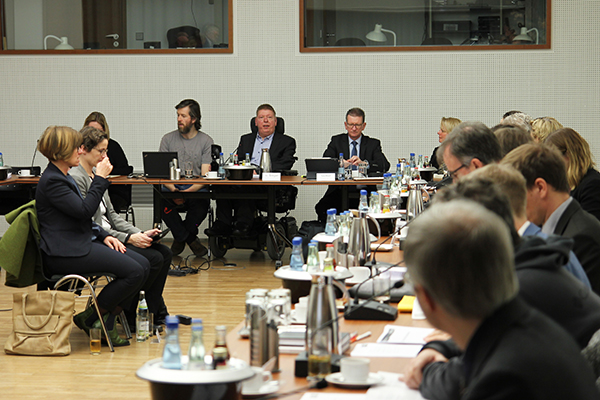 Hinten mittig: Dr. Volker Sieger von der Bundesfachstelle Barrierefreiheit beim Vortrag, links und rechts Sitzungsteilnehmer. Foto: Bundesfachstelle Barrierefreiheit