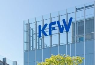Das Bild zeigt die KfW-Zentrale Frankfurt, Außenaufnahme, Haupthaus. Das Haus hat eine Glasfassade, das KFW-Logo hängt rechts oben in der Ecke des Gebäudes, von dem der obere Teil vor blauem Himmel zu sehen ist. Foto: KfW-Bildarchiv / Rüdiger Nehmzow