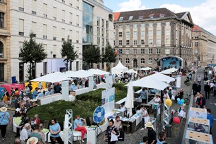 Das Bild zeigt die Informationsstände vom BMAS auf dem Zietenplatz von oben mit weißen Sonnenschirmen und den Besucherinnen und Besuchern